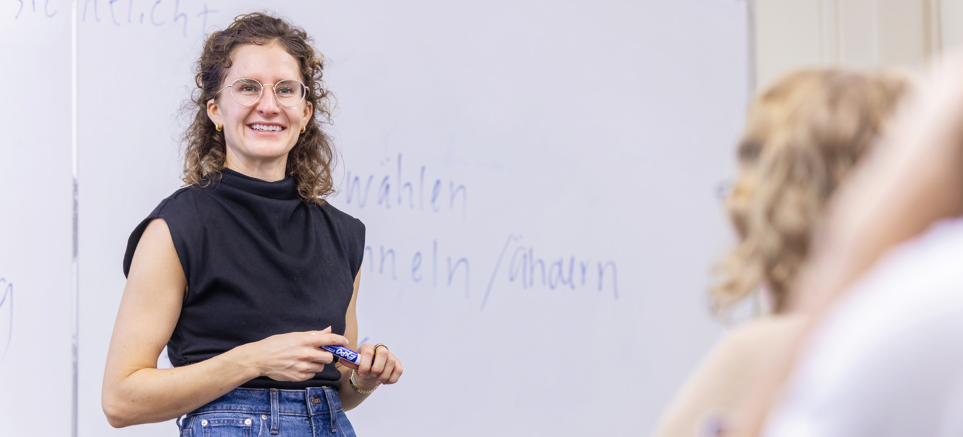 a female professor in front of a whiteboard with German words