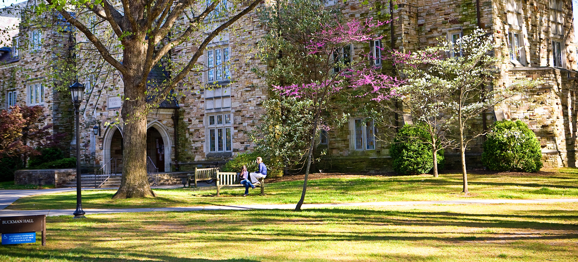 students talk on a bench outside of a Collegiate Gothic building