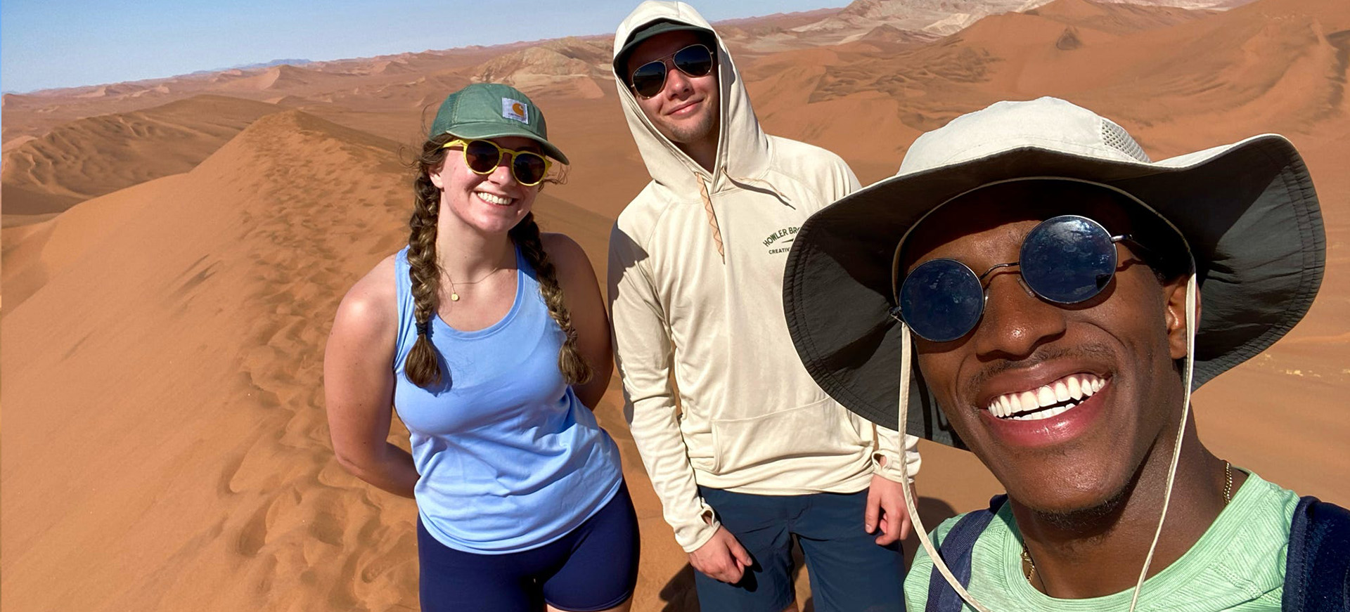 three students on a sand dune in Namibia