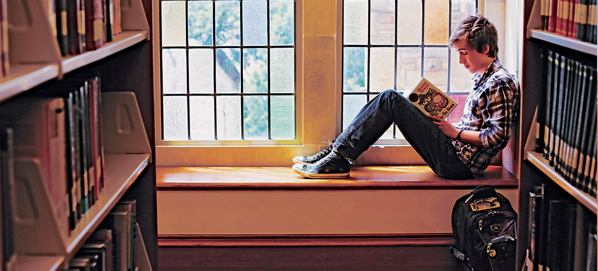 student reading a book in front of a stained glass window