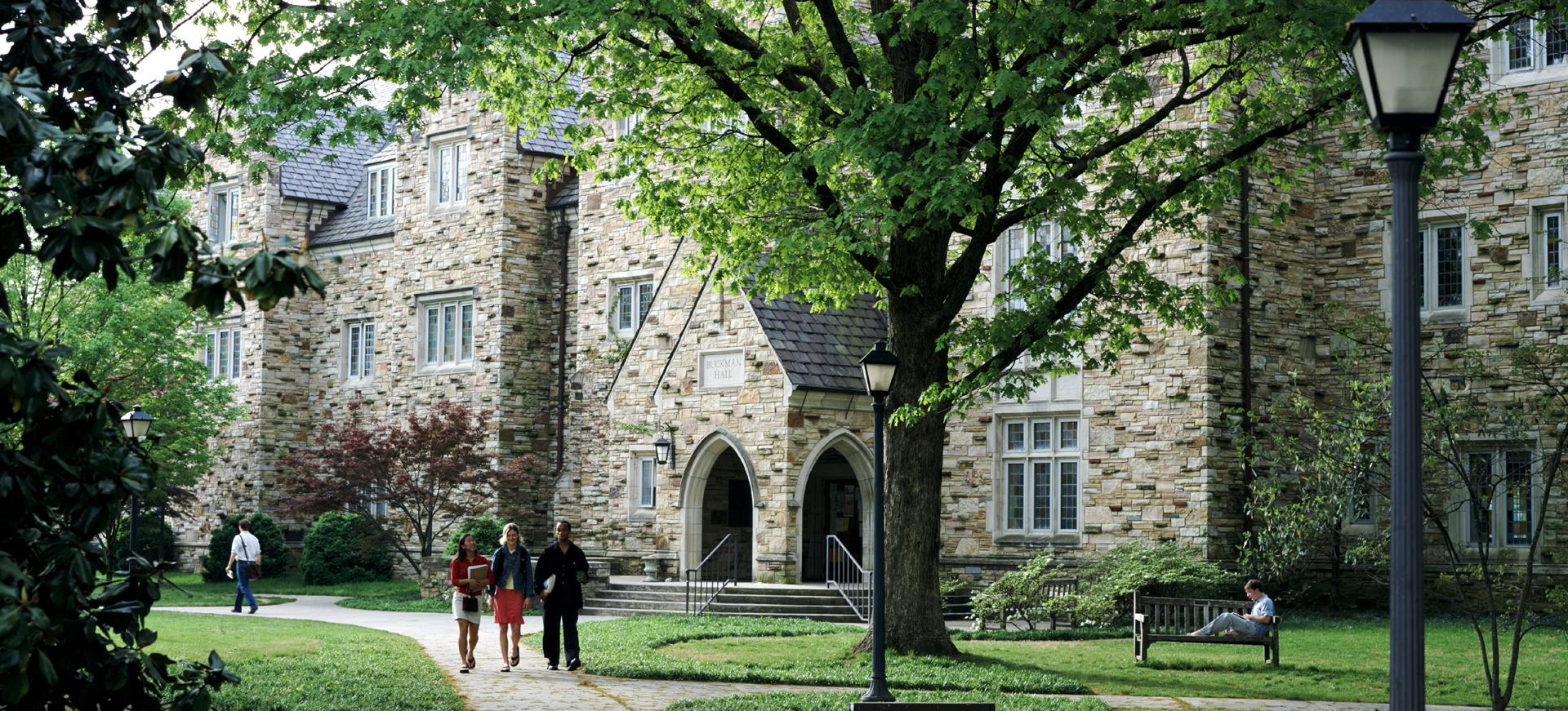 Students walking along a sidewalk in front of a building on Rhodes Campus