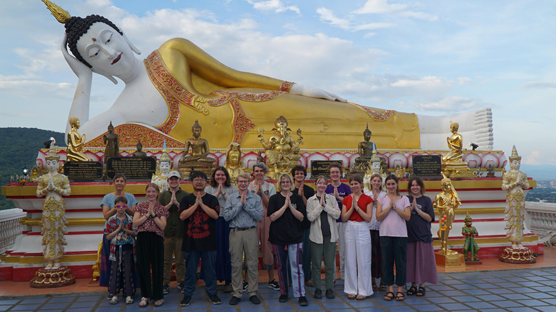 students in front of a large Thai statue
