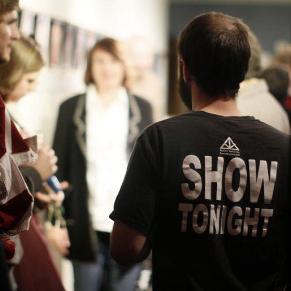 A man with his back to the camera wears a shirt that says Show Tonight