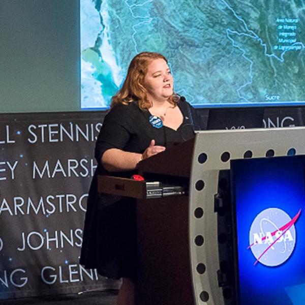 A woman stands behind a futuristic looking lectern.