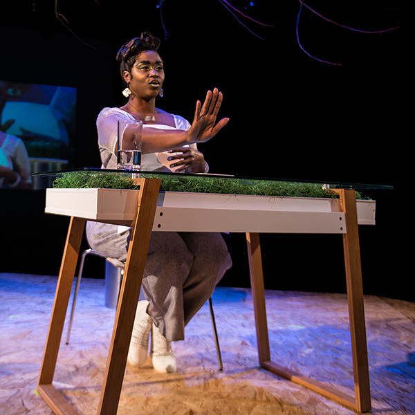 an actress sits at a desk on stage