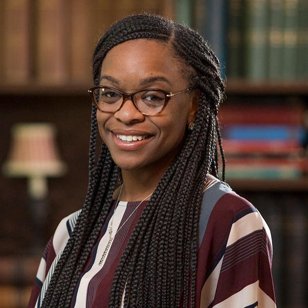 an African American woman with long hair smiles at the camera