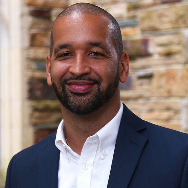 an African American man in a blue suit smiles at the camera