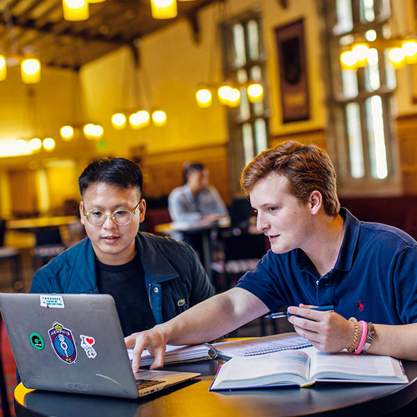 two young men look at a laptop