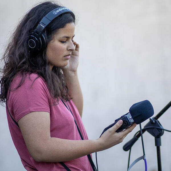 a young woman in headphones holds a microphone