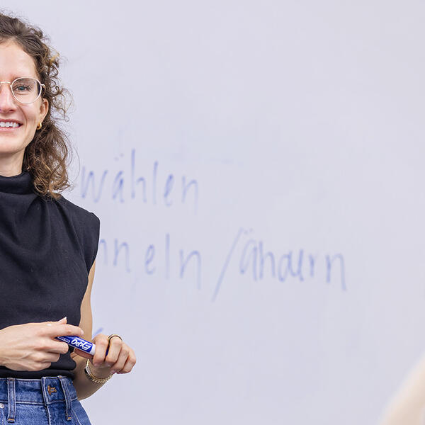 a female professor in front of a whiteboard with German words