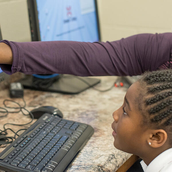 a student helps a young girl study on a computer