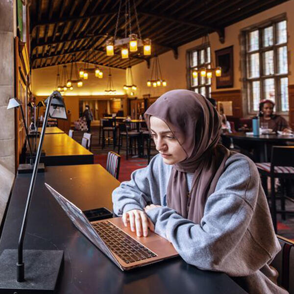 a young woman in a head scarf uses a laptop