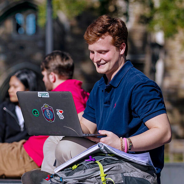 a young man outdoors on a laptop