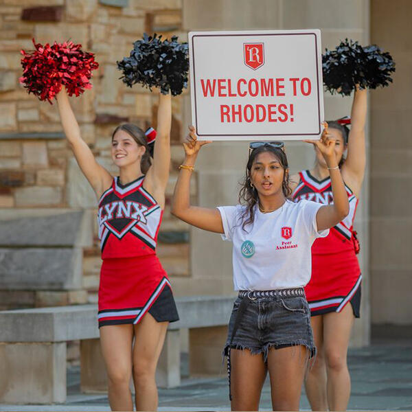 a student holds a sign saying Welcome to Rhodes