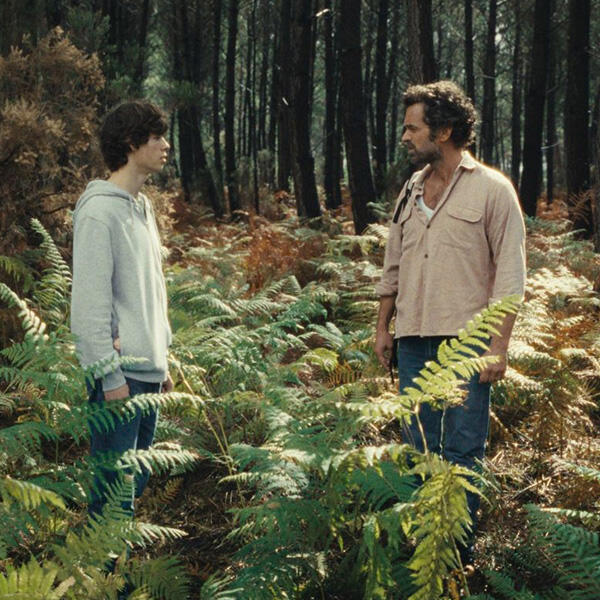 a man and a boy stand in a forest