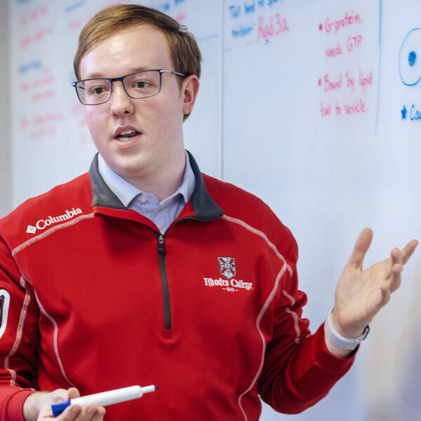 a young man gestures at a whiteboard