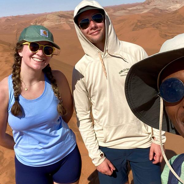 three students on a sand dune in Namibia