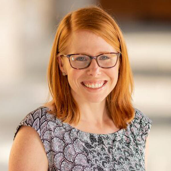 a young woman with red shoulder-length hair and glasses