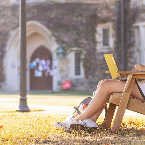 a student works on a laptop in a collegiate quad
