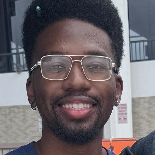 a young Black man smiles at the camera