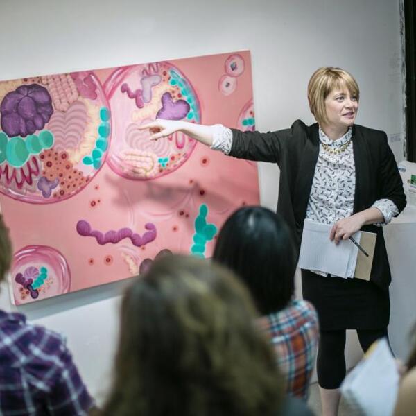 A professor points to a pink painting