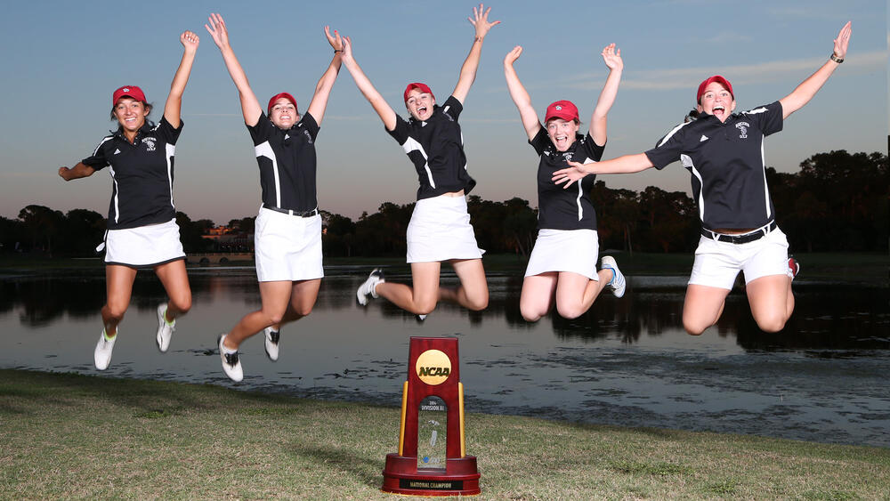 female golf team celebrate with the NCAA trophy
