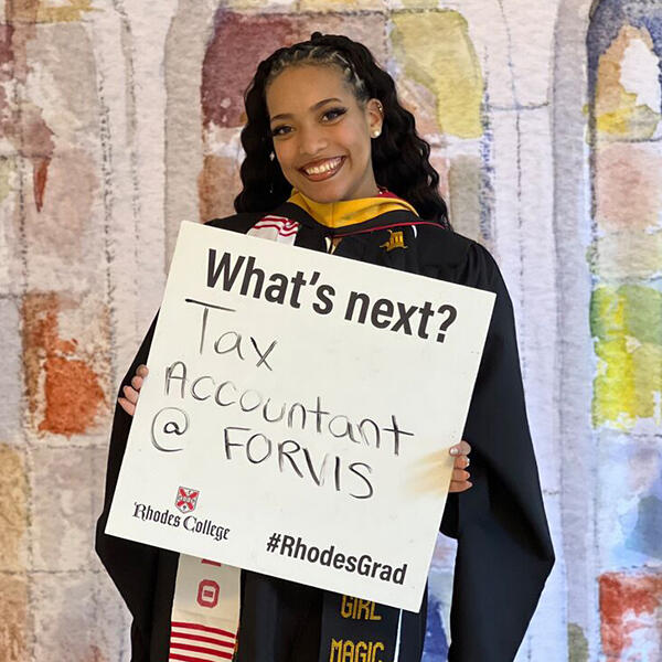 a student holds a sign that says tax analyst