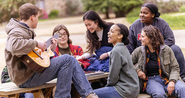 a student plays guitar while others gather around